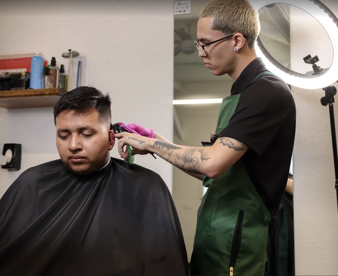 A Cultura barber running clippers through a fresh fade under a ring light